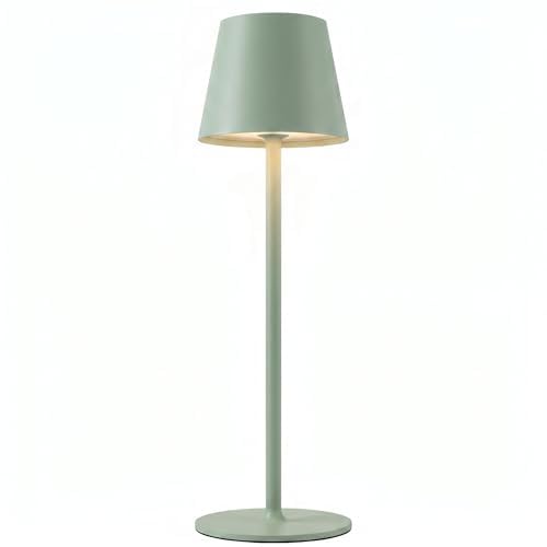Lampe de table verte à abat-jour rond posée sur une table en bois, dans une lumière douce
