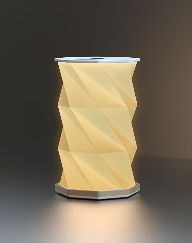 Lampe de table blanche pliable inspirée de l’origami, posée sur une table en bois.