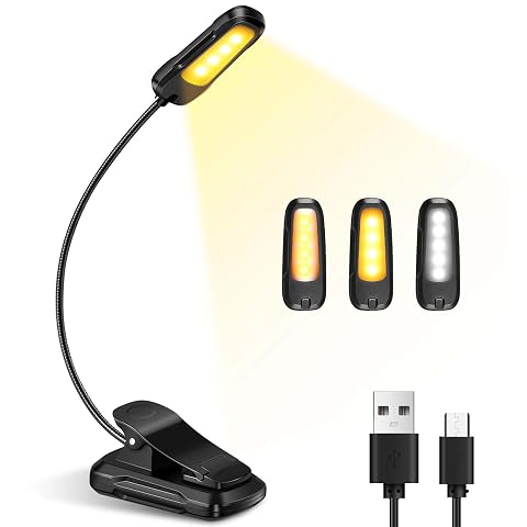 Petite lampe de lecture à pince fixée à un livre ouvert, avec col flexible orienté vers les pages.