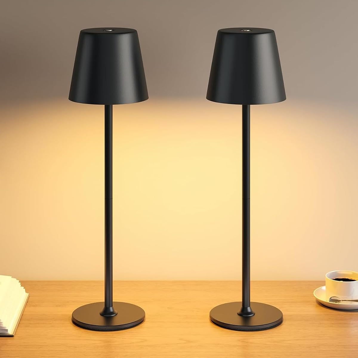 Deux lampes de table noires en métal, à abat-jour cylindrique, posées sur une table en bois.