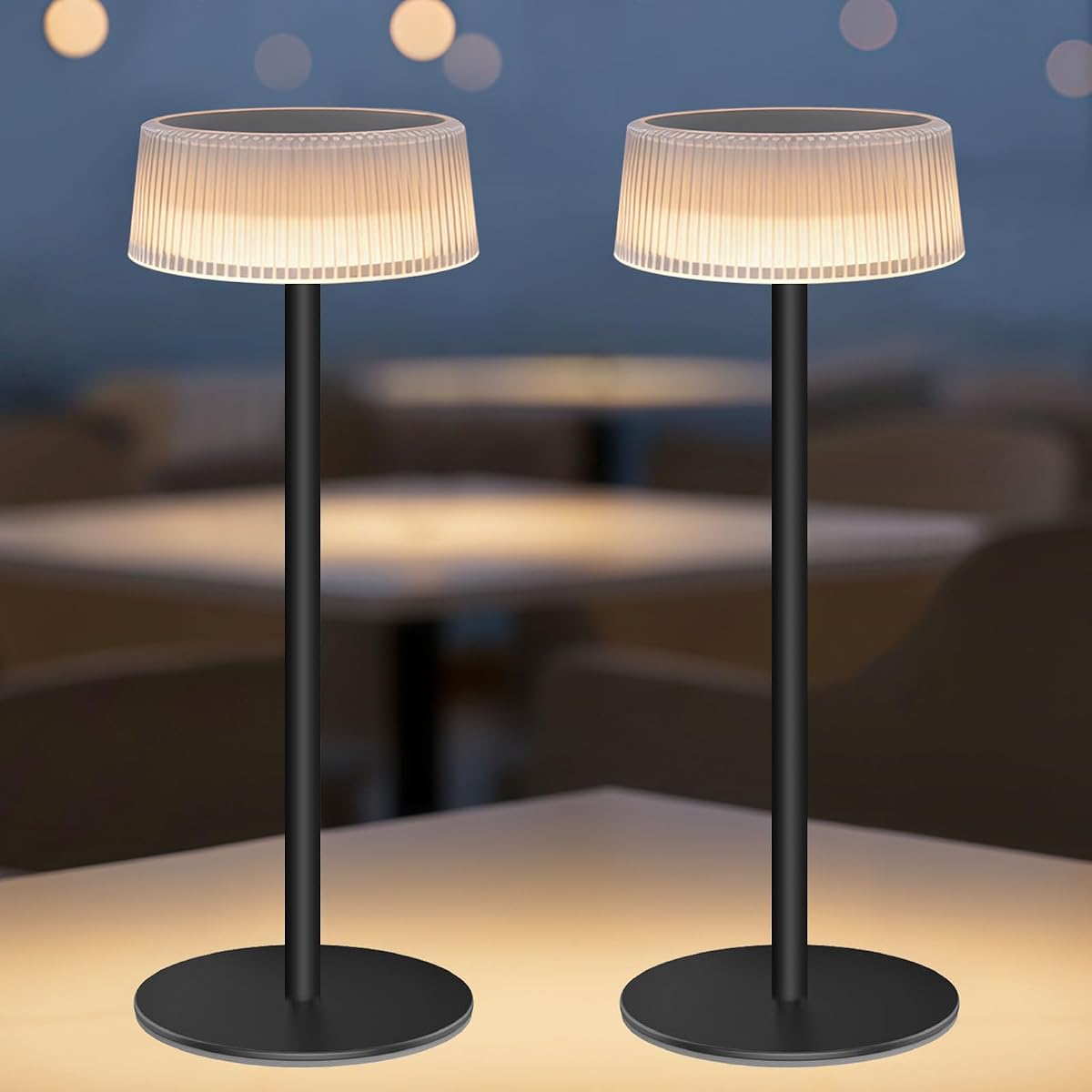 Deux lampes de table solaires en métal et acrylique transparent posées sur une table en bois.