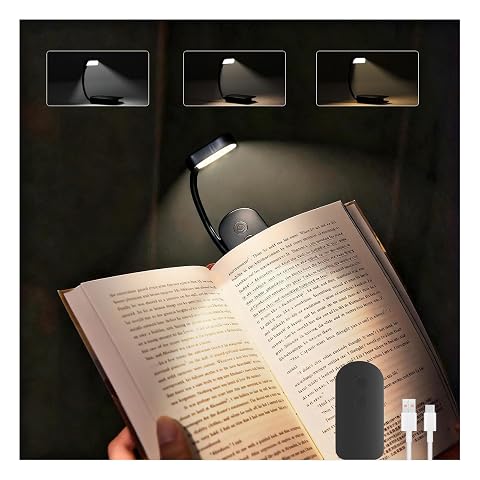 Lampe de lecture noire à pince fixée sur un livre ouvert, posée sur une table en bois