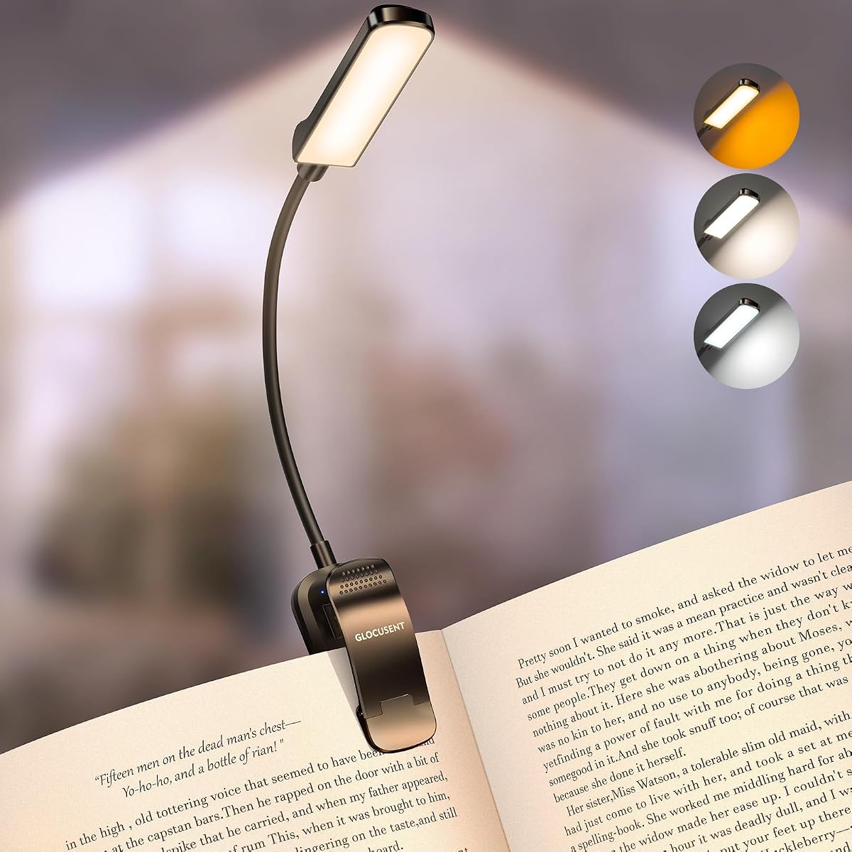 Lampe de lecture noire à pince orientable fixée sur un livre ouvert posé sur une table en bois