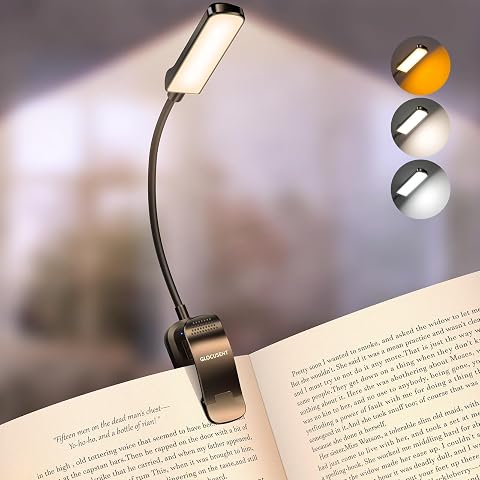 Lampe de lecture noire à pince orientable fixée sur un livre ouvert posé sur une table en bois