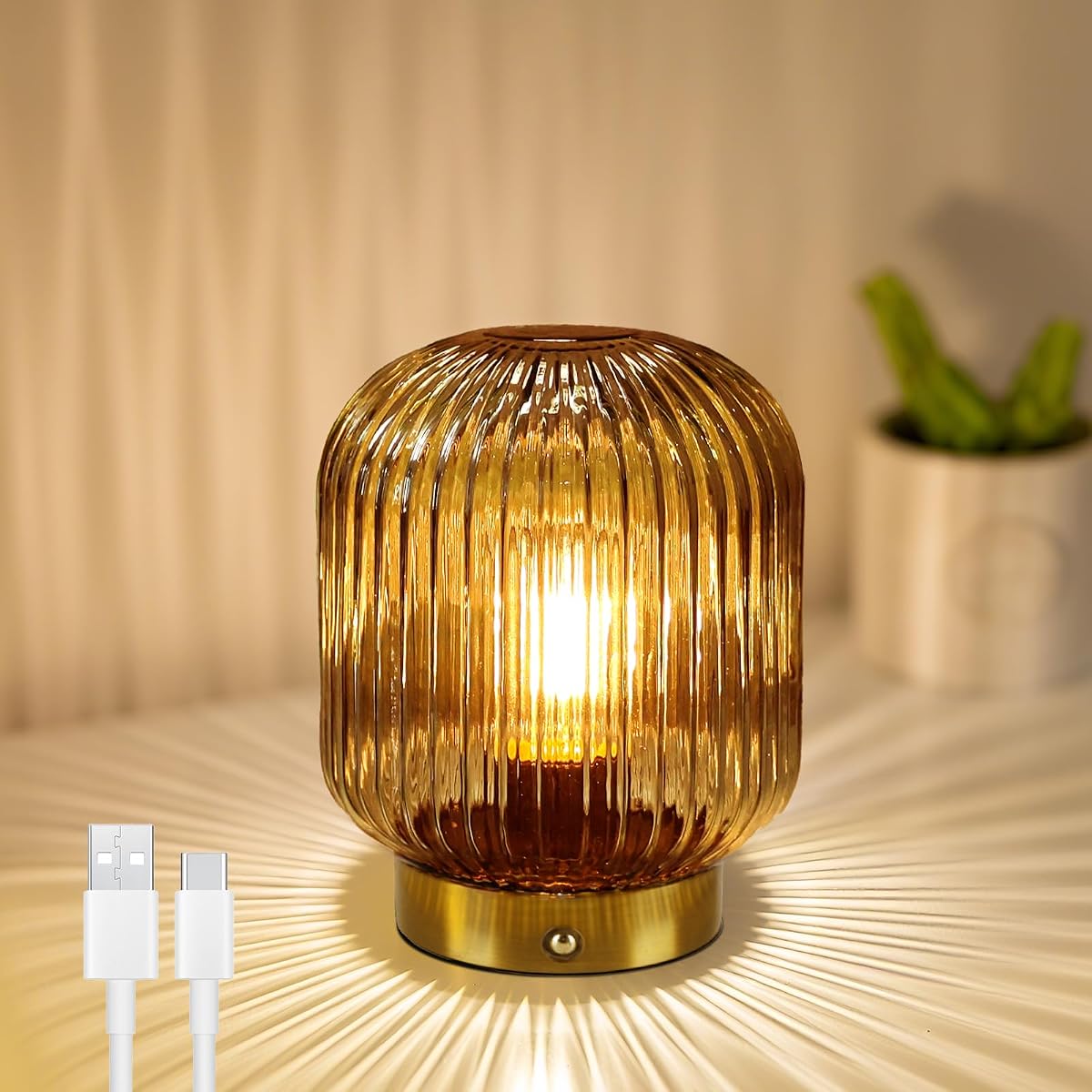 Lampe de table compacte en verre jaune et base métallique, allumée sur une table en bois.