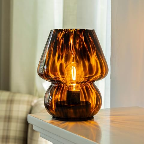 Lampe champignon en verre ambre avec motif léopard translucide, posée sur une table en bois