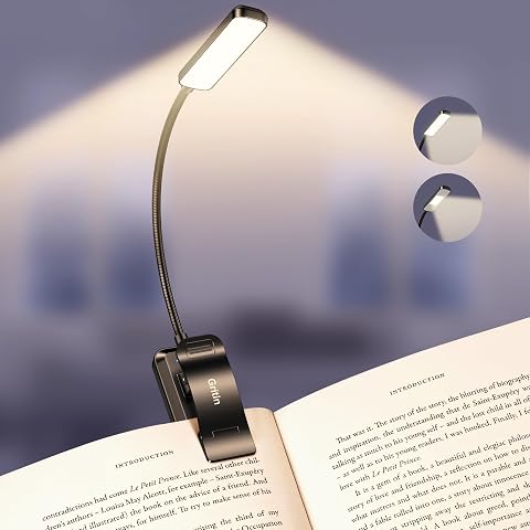 Lampe de lecture noire à pince fixée à un livre ouvert, avec col flexible orienté vers les pages