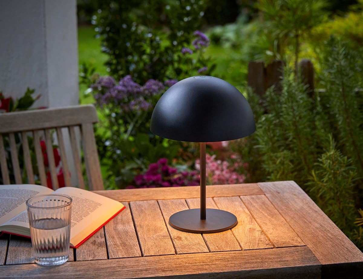 Lampe de table LED noire en forme de champignon posée sur une table en bois